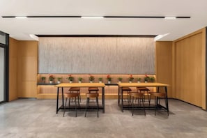 A modern dining area with two tables, chairs, and a wall-mounted planter with red flowers. - Vienna Classic Hotel (Qingdao Golden Beach Wuyue Plaza) (Qingdao)