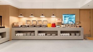A modern reception area with a counter, shelves with plates, and hanging pendant lights. - Vienna Classic Hotel (Qingdao Golden Beach Wuyue Plaza) (Qingdao)