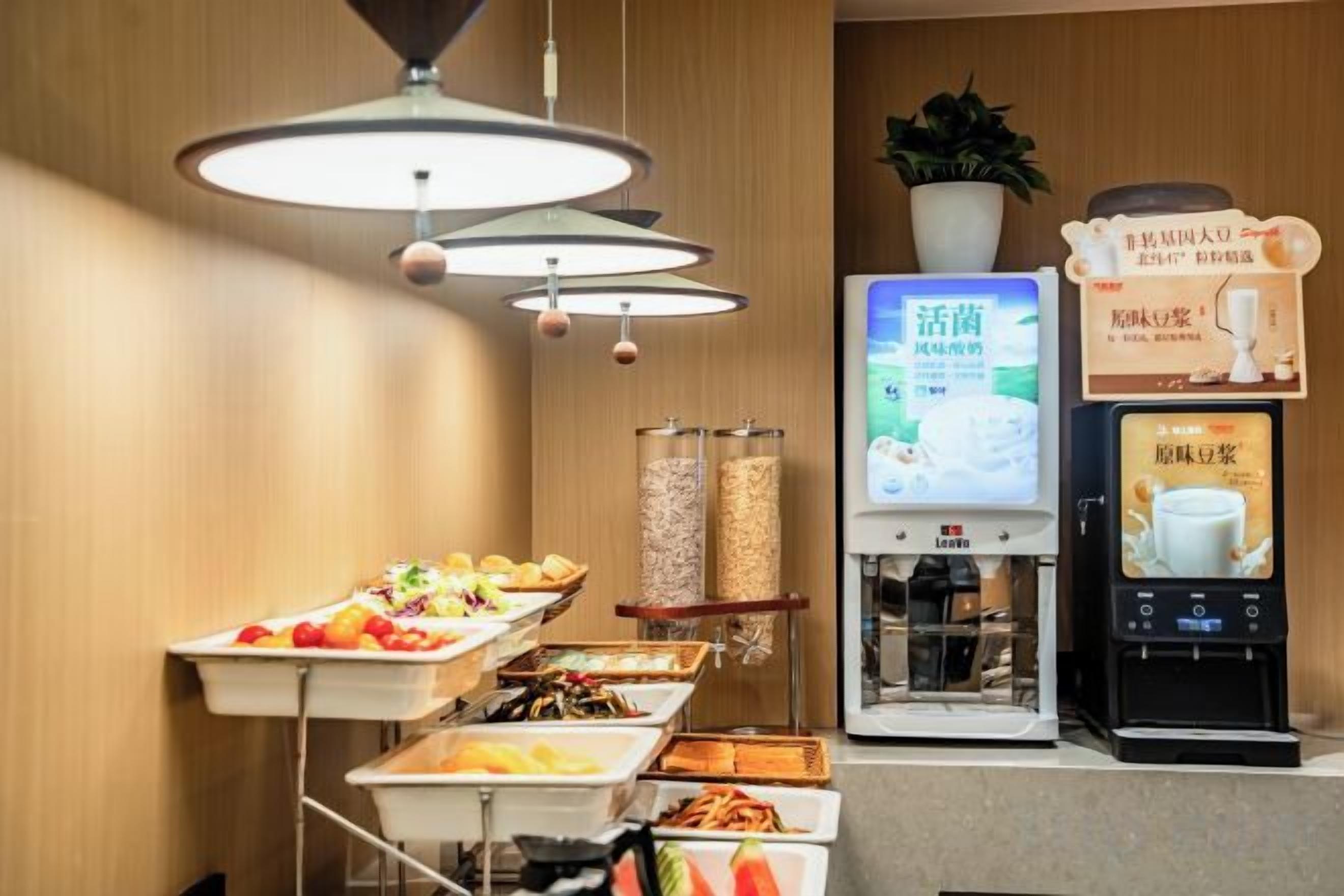 A buffet area with various food options, a coffee machine, and a digital menu display.