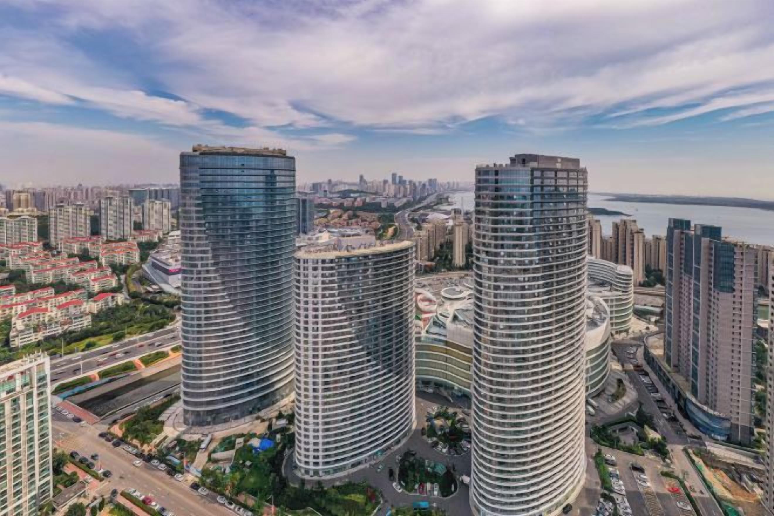 A high-rise building complex with multiple skyscrapers, a waterfront view, and a cityscape in the background.