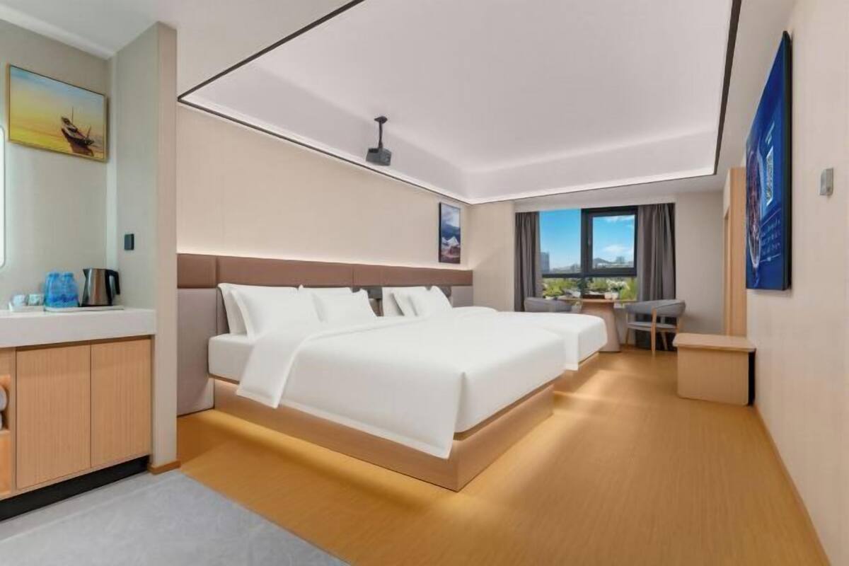 A modern hotel room with a large bed, a desk, and a view of the outdoors.