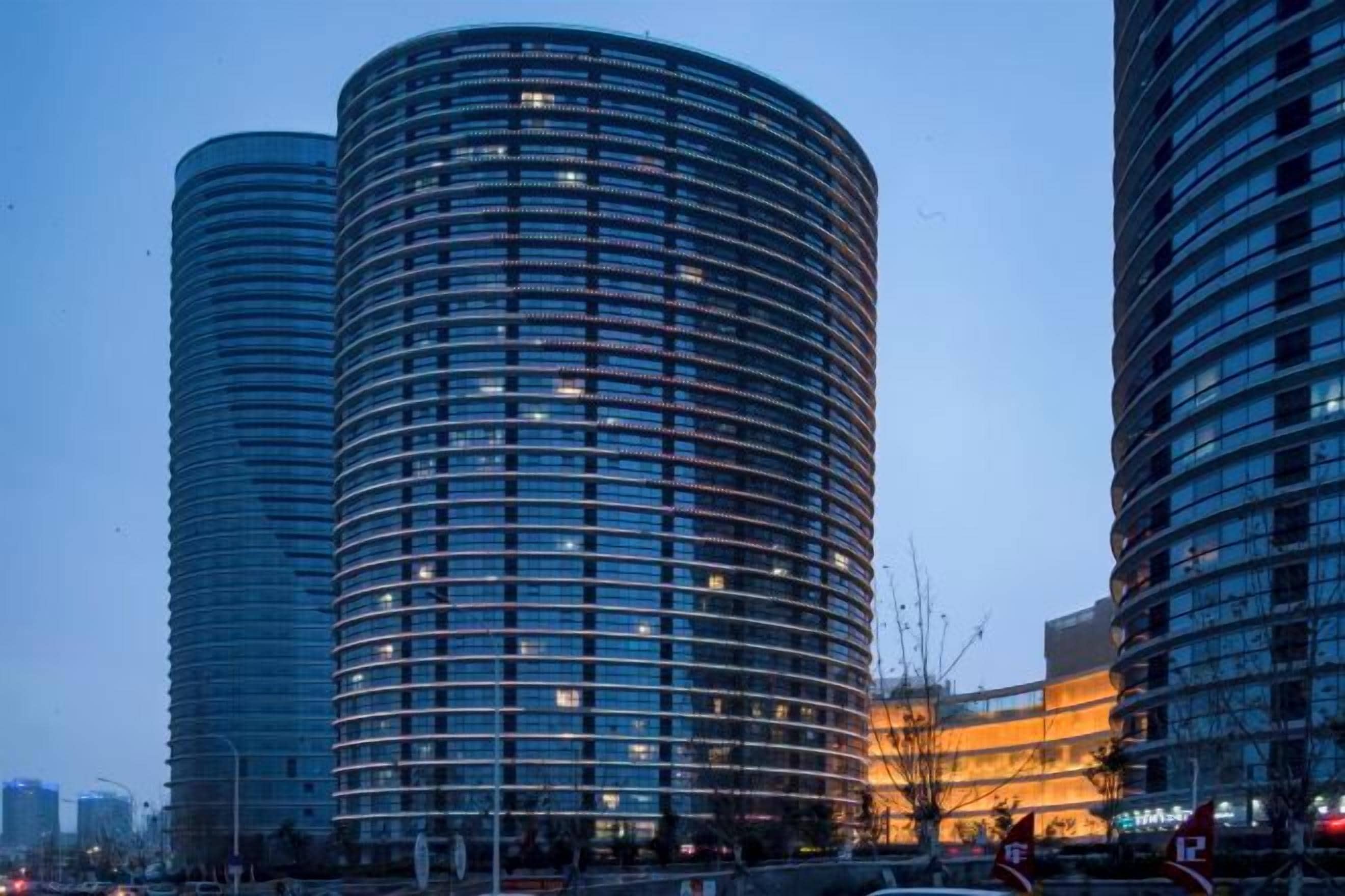 Two cylindrical high-rise buildings with a modern architectural design, featuring a series of balconies and a uniform facade.