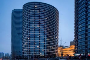 Two cylindrical high-rise buildings with a modern architectural design, featuring a series of balconies and a uniform facade. - Vienna Classic Hotel (Qingdao Golden Beach Wuyue Plaza) (Qingdao)