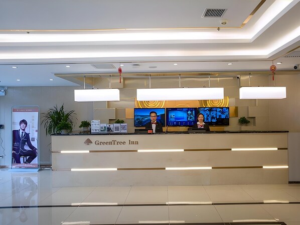 A hotel reception desk with a modern design, including a flat-screen TV display and a digital information kiosk. - Greentree Inn Tongchuan Yaozhou District New District Hospital Business Hotel (Tongchuan)