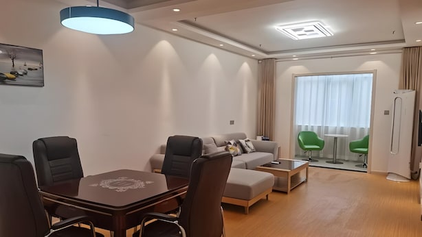 Una sala de estar moderna con comedor, sofá, mesa de centro y un ventanal con cortinas.