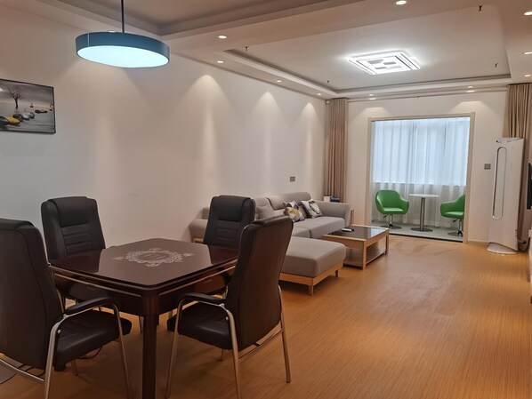 Una sala de estar moderna con comedor, sofá, mesa de centro y un ventanal con cortinas.