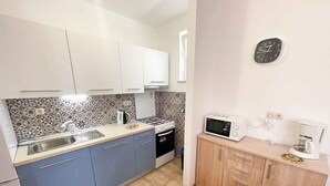 A compact kitchen with a sink, stove, microwave, and coffee maker.