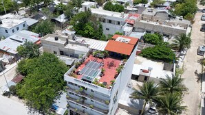 Ein mehrstöckiges Hotel mit Dachterrasse, Balkonen und einem Parkplatz.