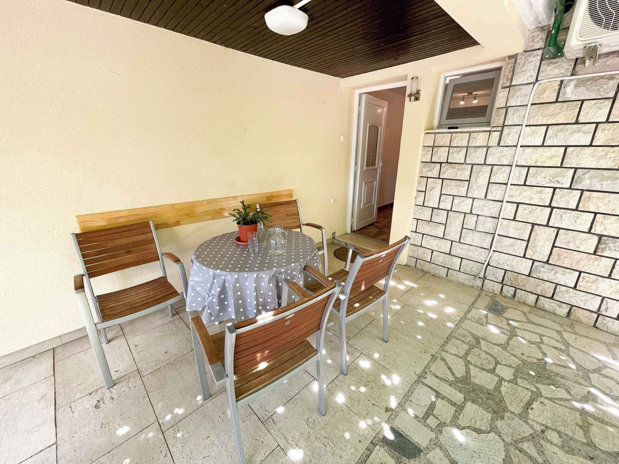 A round table with a polka dot tablecloth, surrounded by wooden chairs, in a room with a stone wall and a ceiling fan.