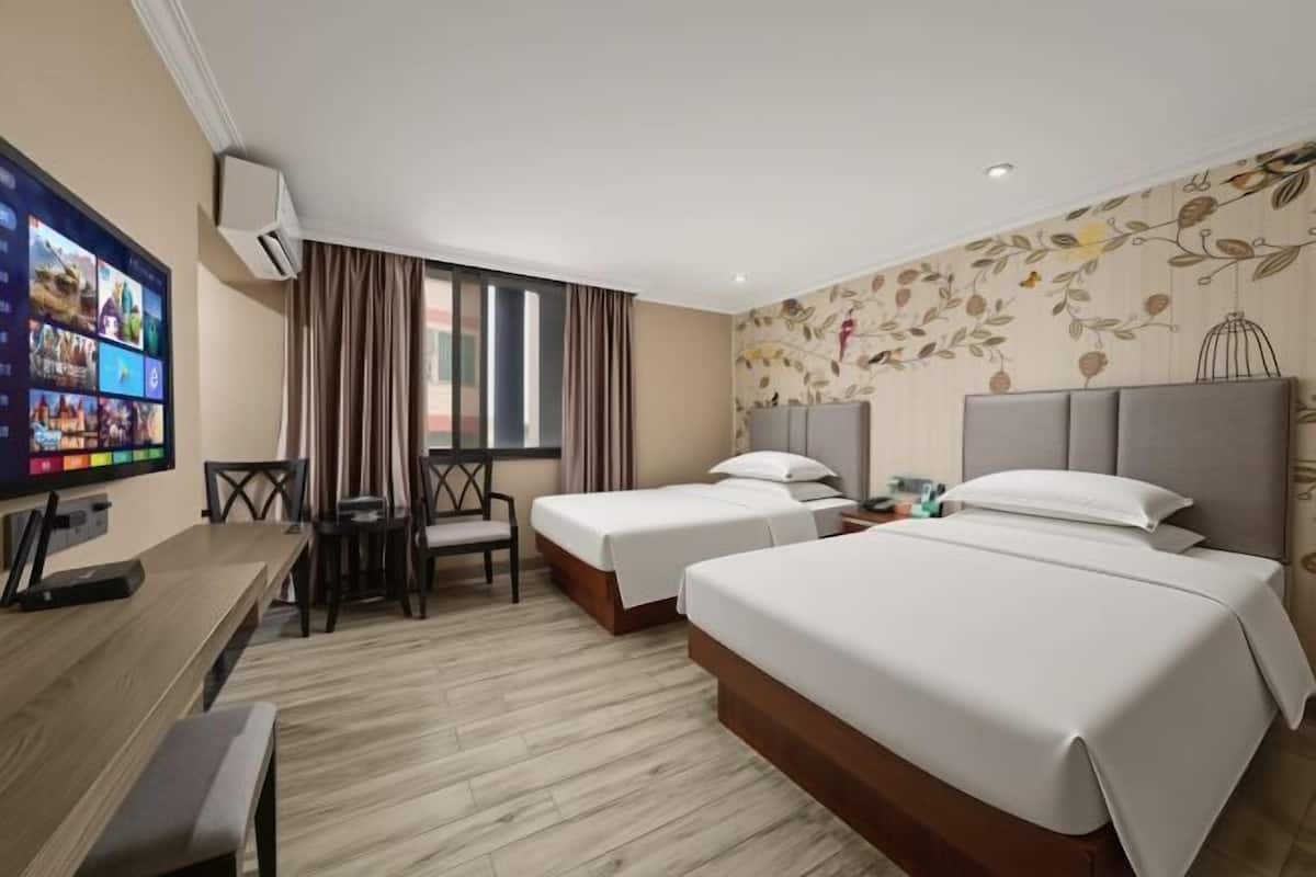 A hotel room with two beds, a desk with a chair, a TV, and a window with curtains.