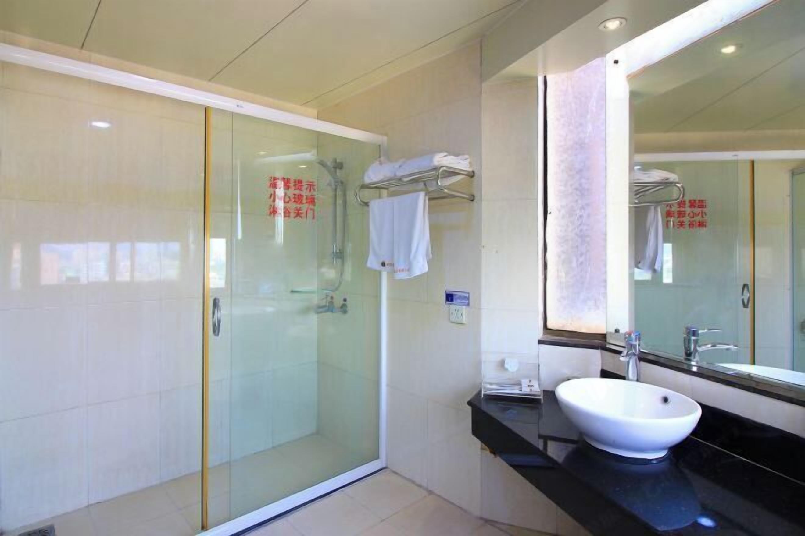 Ein modernes Badezimmer mit Duschkabine aus Glas, einem weißen Waschbecken und einem großen Spiegel.