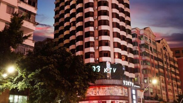 A tall, cylindrical building with a prominent sign reading "93 KTV" at the bottom. - Jiangmen Park Lane Yiju Hotel (Wuyi University Jianshe Road) (Jiangmen)