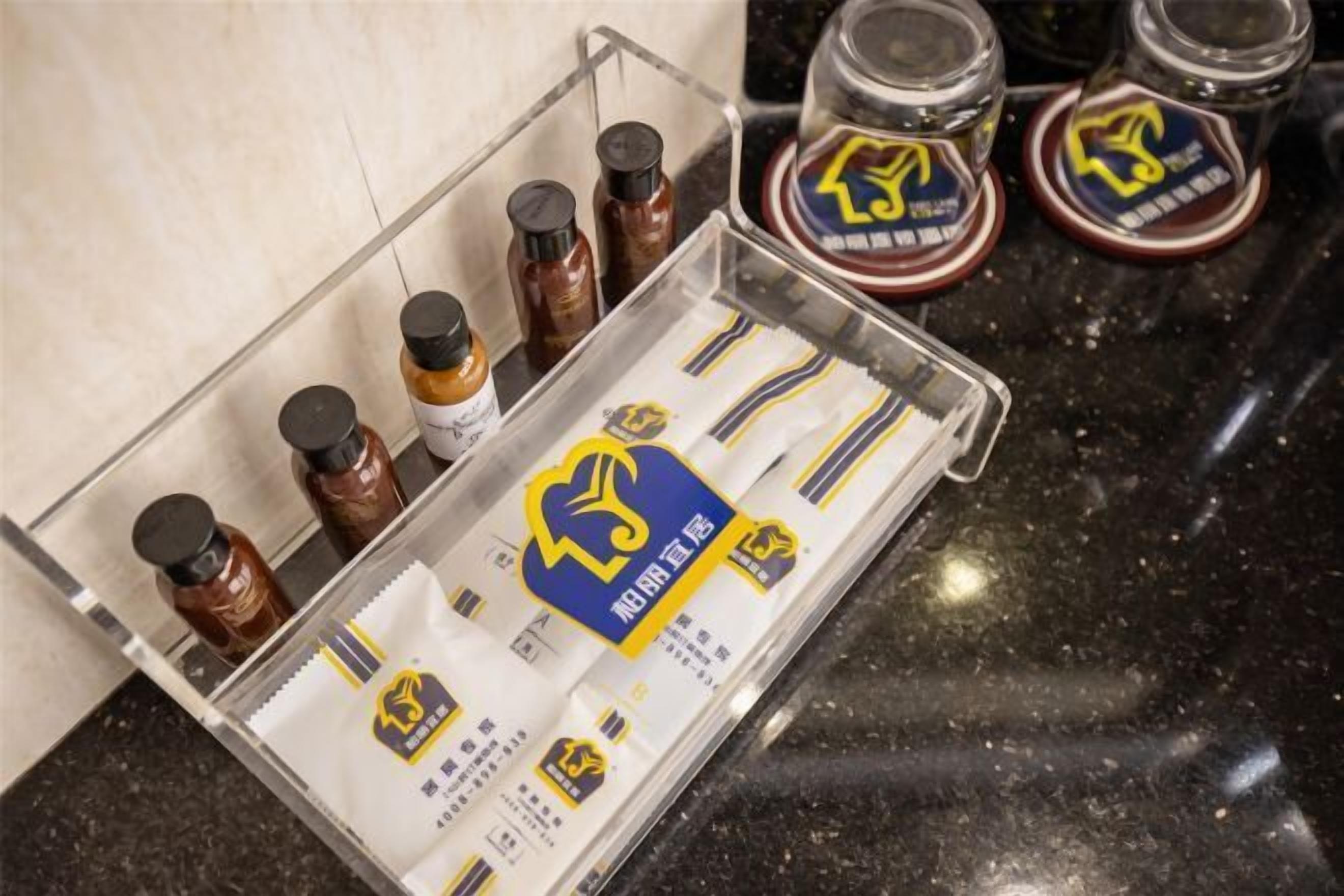 Una encimera de cocina con un organizador de plástico transparente que contiene sobres de condimentos y frascos de salsas.