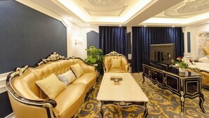 Een luxueuze kamer met een goudkleurige bank, een bijpassende fauteuil, een salontafel en een televisie.