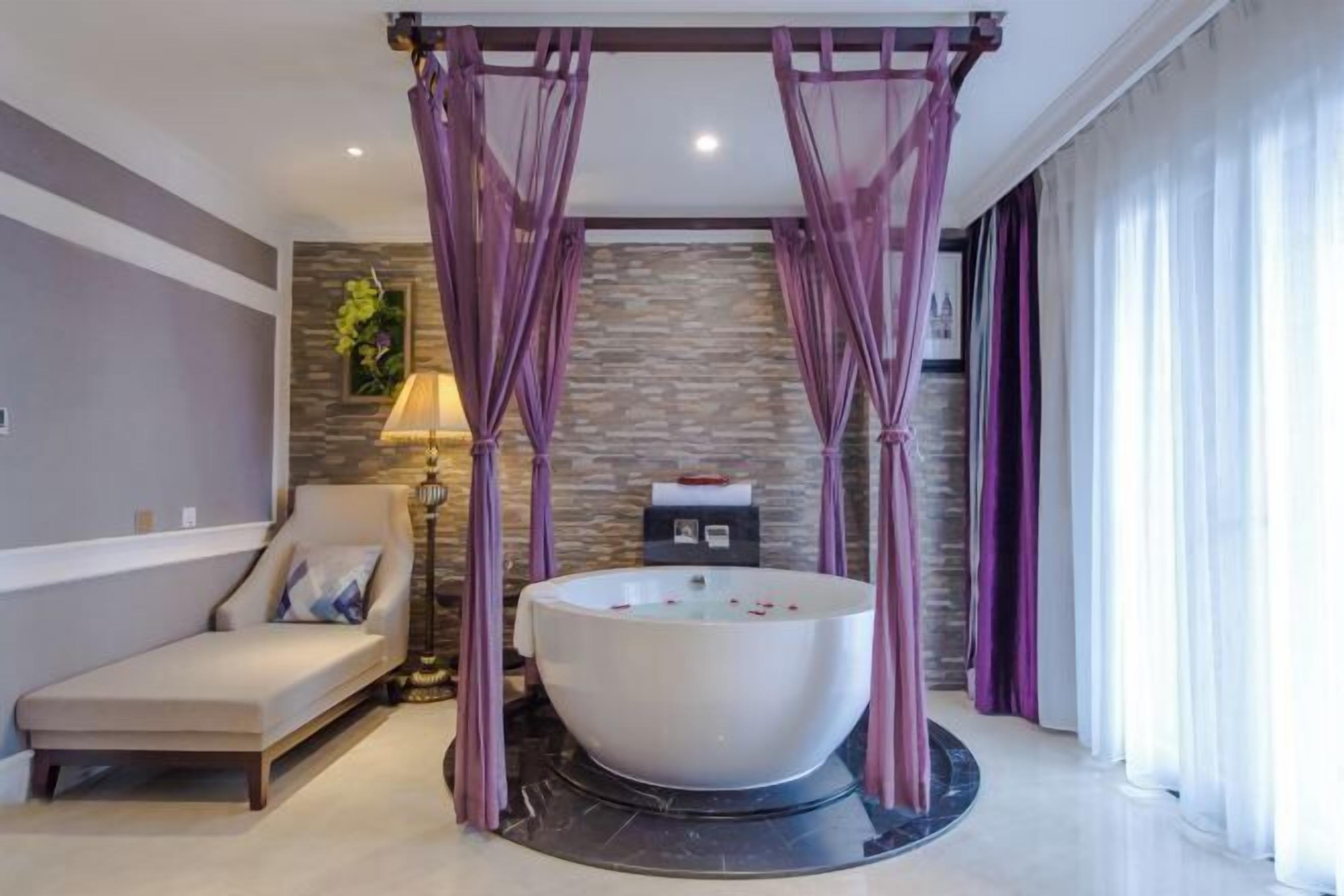 A modern bathroom with a freestanding bathtub, a massage chair, and a stone wall backdrop.
