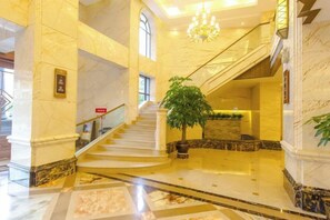 A grand lobby with marble flooring, a staircase, and a reception desk.
