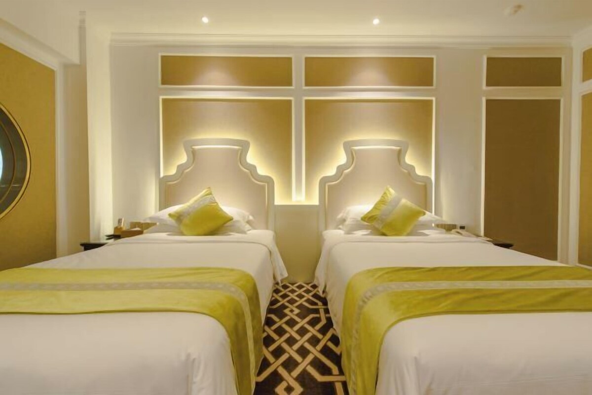 A hotel room with two beds, a patterned floor, and a decorative wall panel.