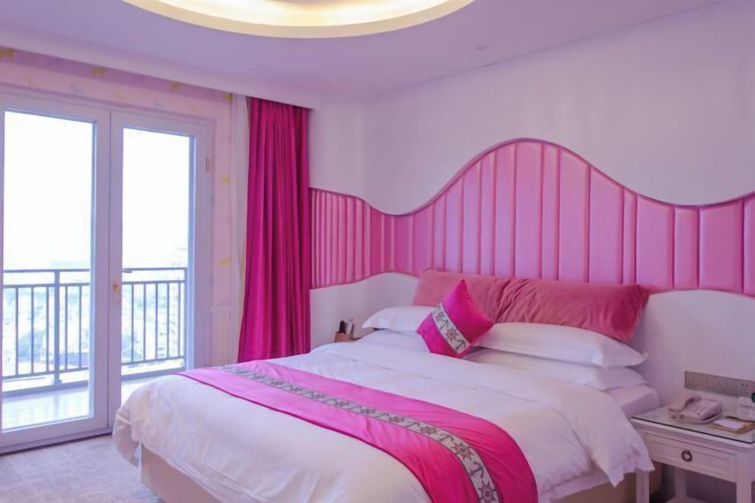Habitación de hotel con una cama, mesita de noche, teléfono y vistas al exterior.