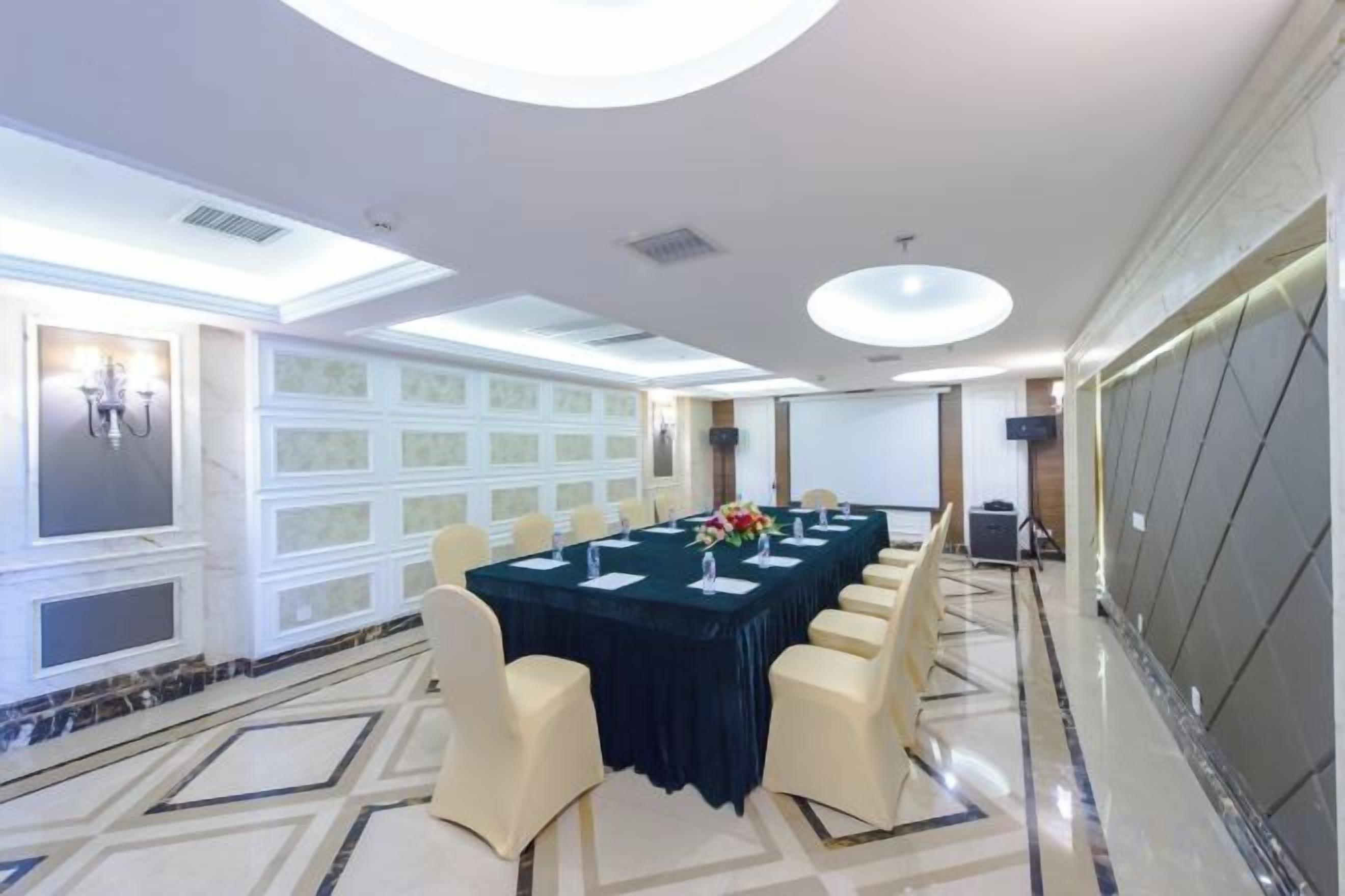 Une salle de conférence avec une longue table, des chaises et un lustre.