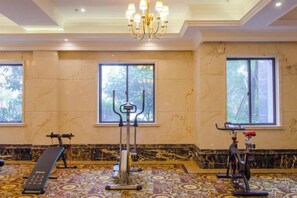 A gym with exercise equipment, large windows, and a chandelier.