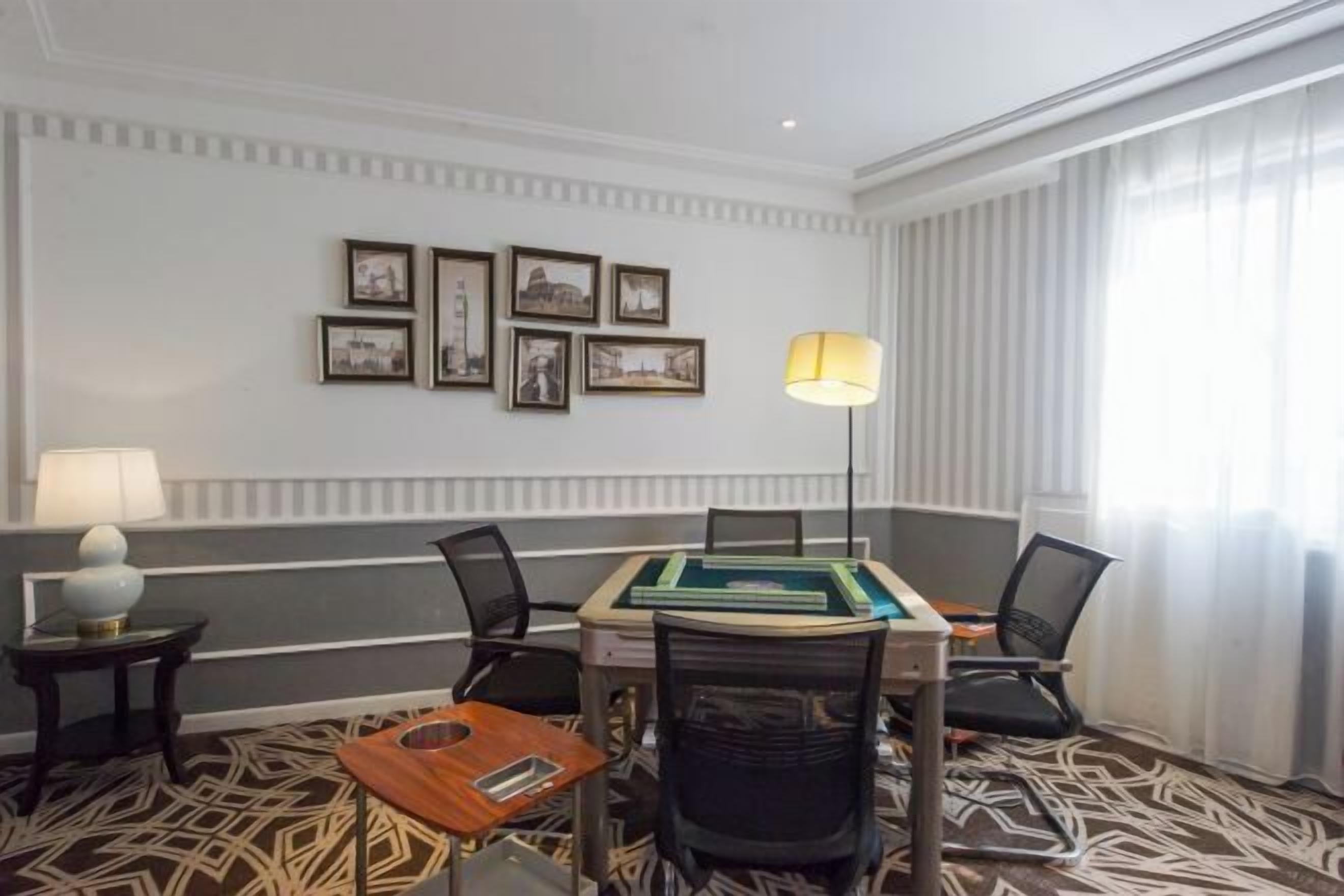 A conference room with a table, chairs, framed pictures on the wall, and a lamp.
