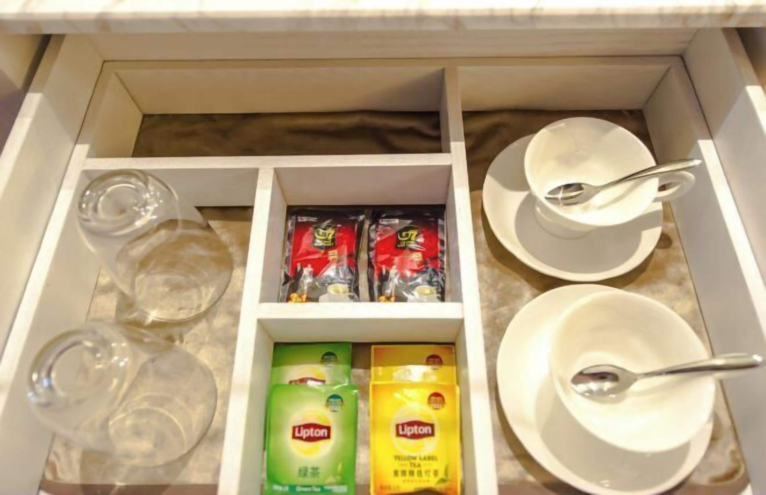 A drawer with tea packets, glasses, and cups.