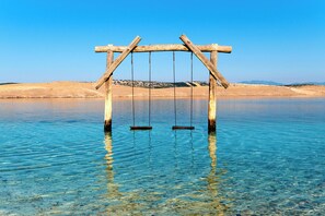 A wooden swing set over clear water with a sandy shore in the background. - Studio with sea view (Dramalj)