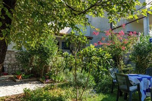 A garden with a stone pathway, potted plants, and a table with chairs.