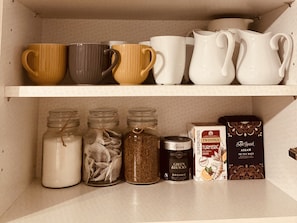 A shelf with various kitchenware items including mugs, a pitcher, and containers with spices. - Capella Cottage, 2 Bedroom, Sleeps 4 (Lincoln)
