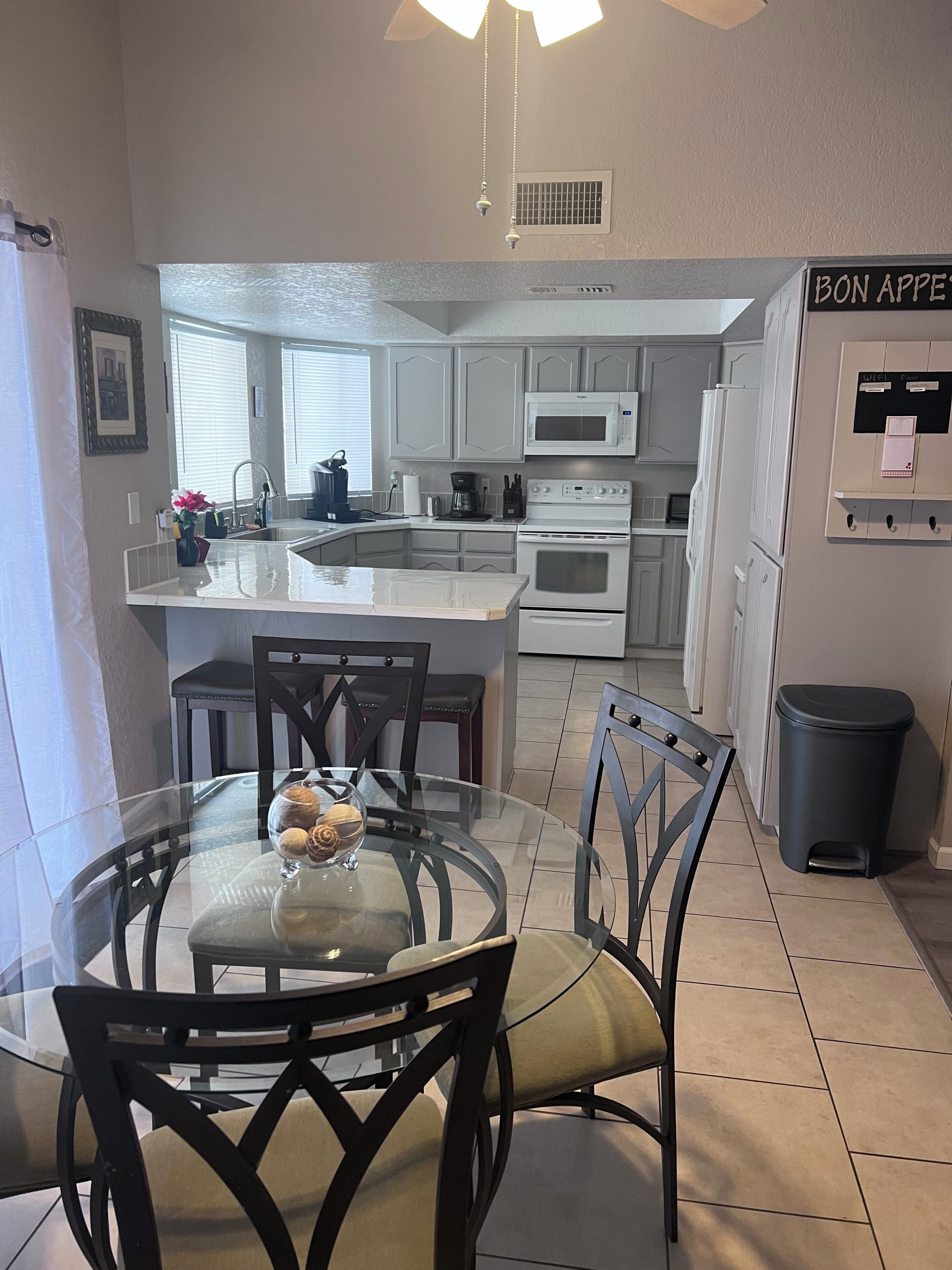 A modern kitchen with white cabinets, a microwave, an oven, and a dining area with a glass table and chairs.