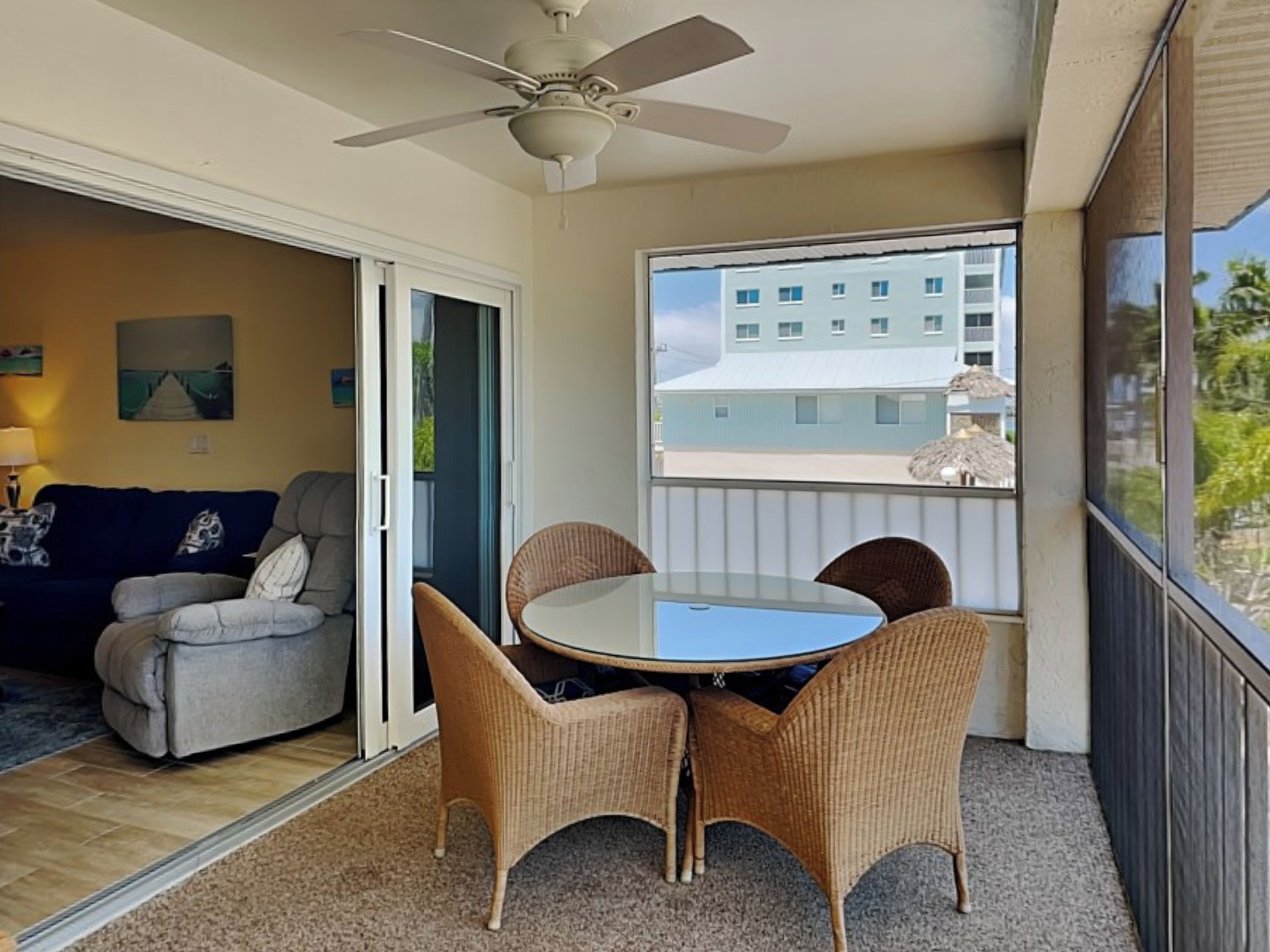 A balcony with wicker furniture, a ceiling fan, and a view of a building.