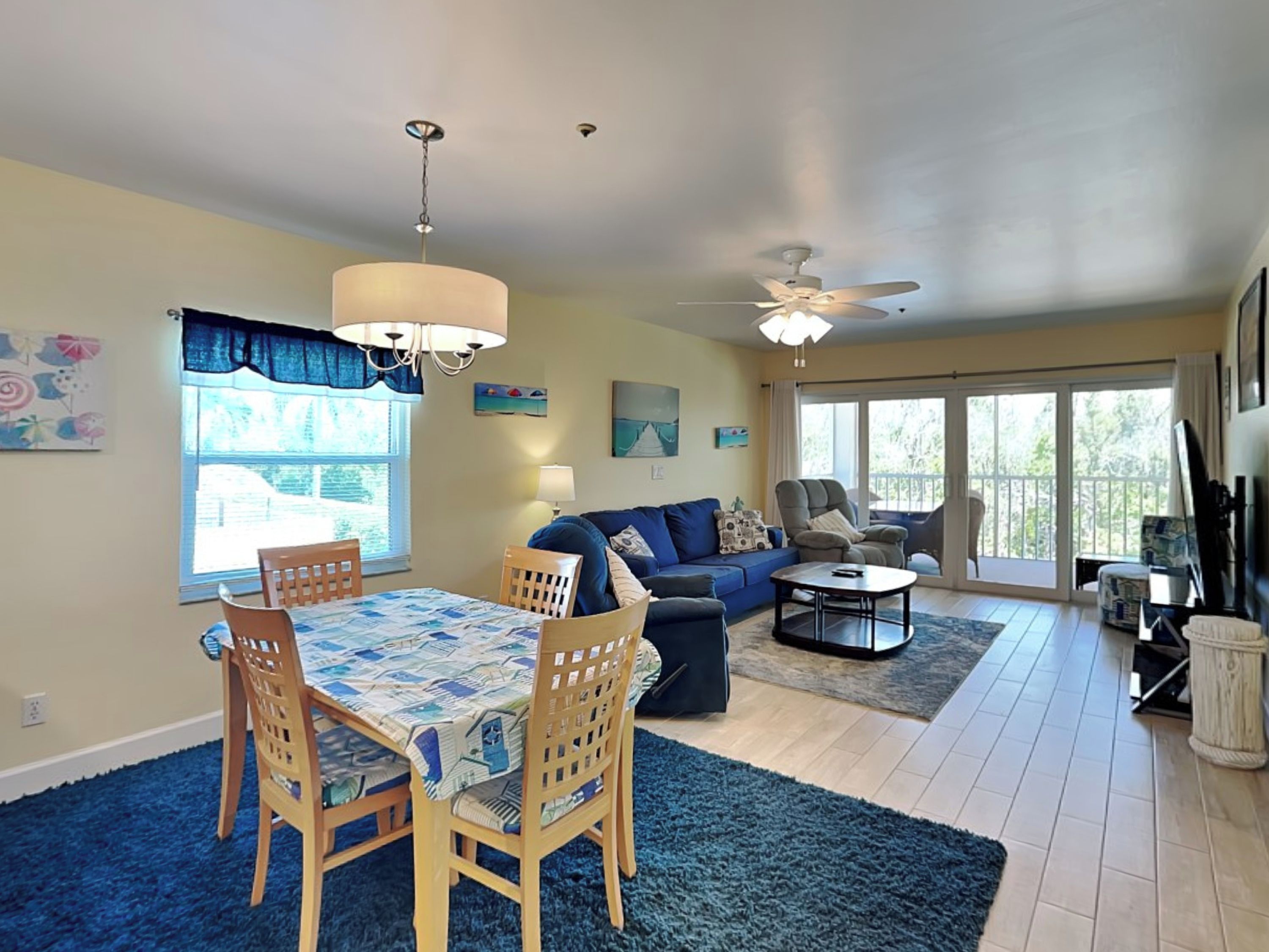A spacious living area with a dining table, chairs, a sofa, and a ceiling fan.
