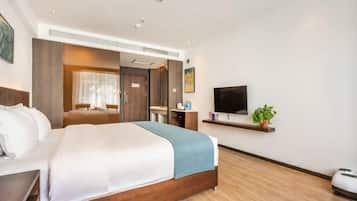 Una habitación de hotel con una cama grande, televisión, escritorio pequeño y una planta.