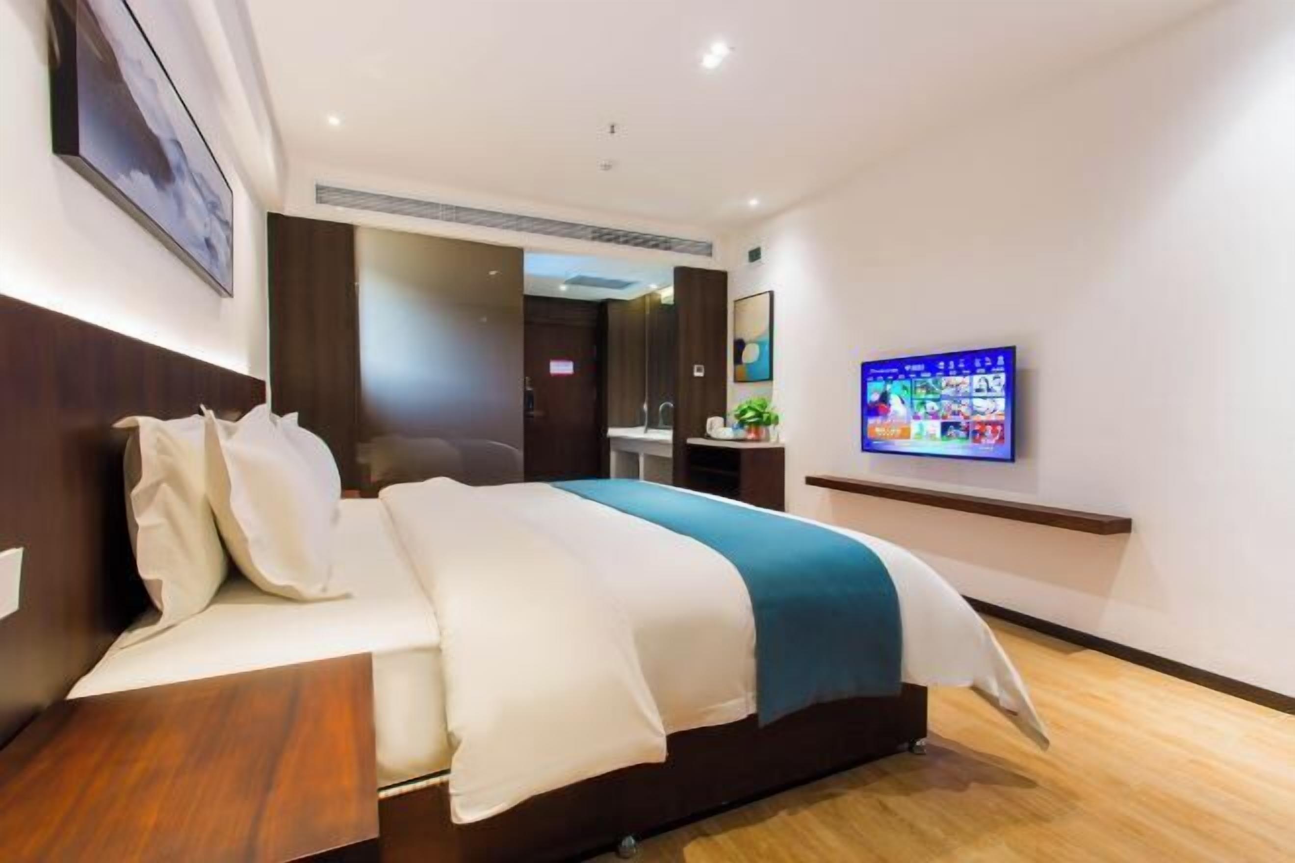 A hotel room with a bed, a TV, a desk, and a mirror.