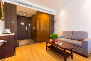 Un hall de hotel con una recepción, un sofá, una mesita con una planta y un perchero.