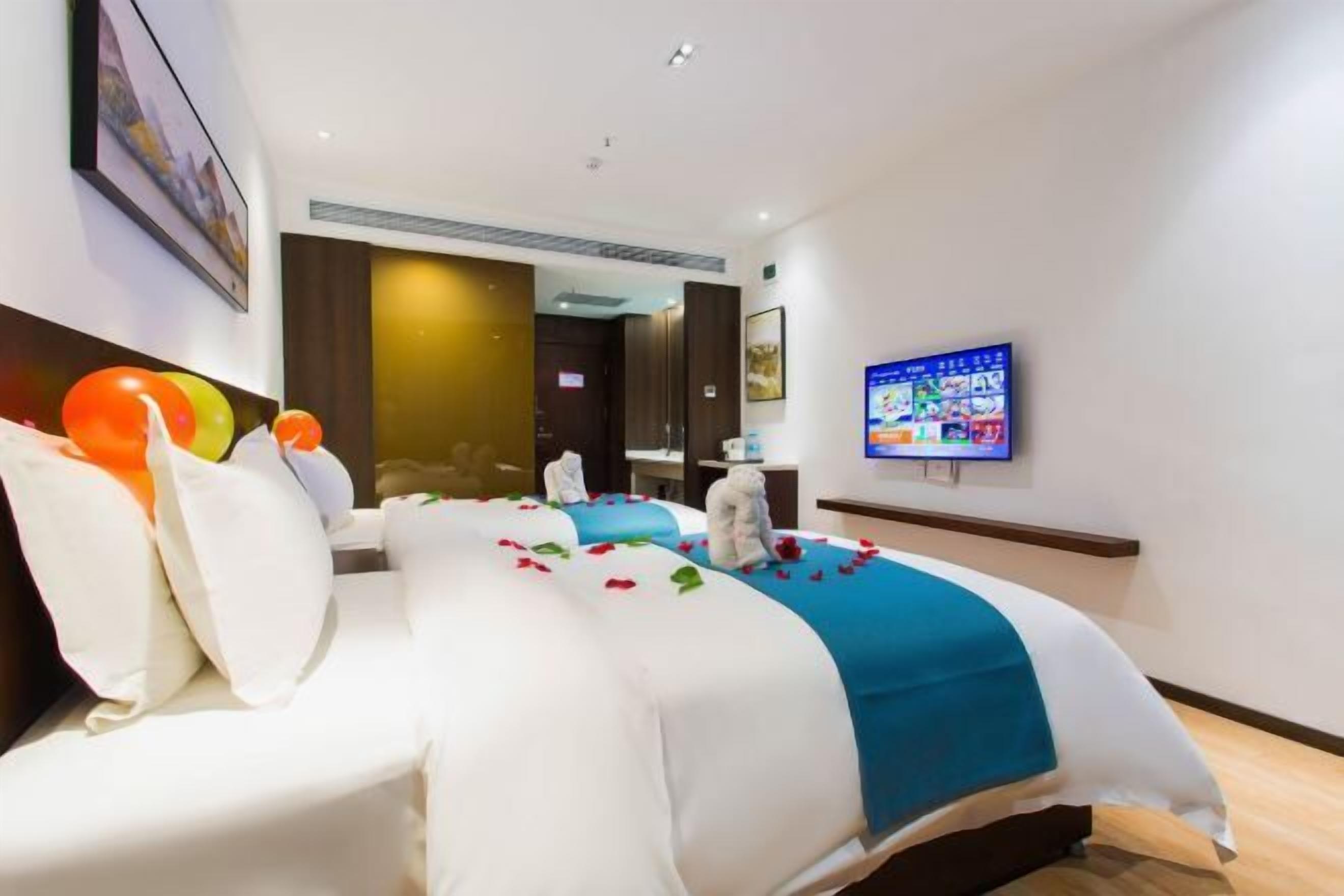 A hotel room with a large bed, a flat-screen TV, and a wall-mounted artwork.