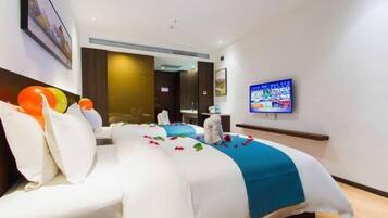 A hotel room with a large bed, a flat-screen TV, and a wall-mounted artwork.