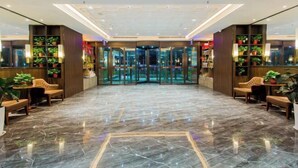 A lobby with a marble floor, wooden furniture, and potted plants. - Jinyue Hotel (Yan'an)