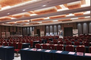 A conference room with rows of tables and chairs, nameplates, and a stage area. - Guohui Hotel (Minhou Ganzhe) (Minhou)