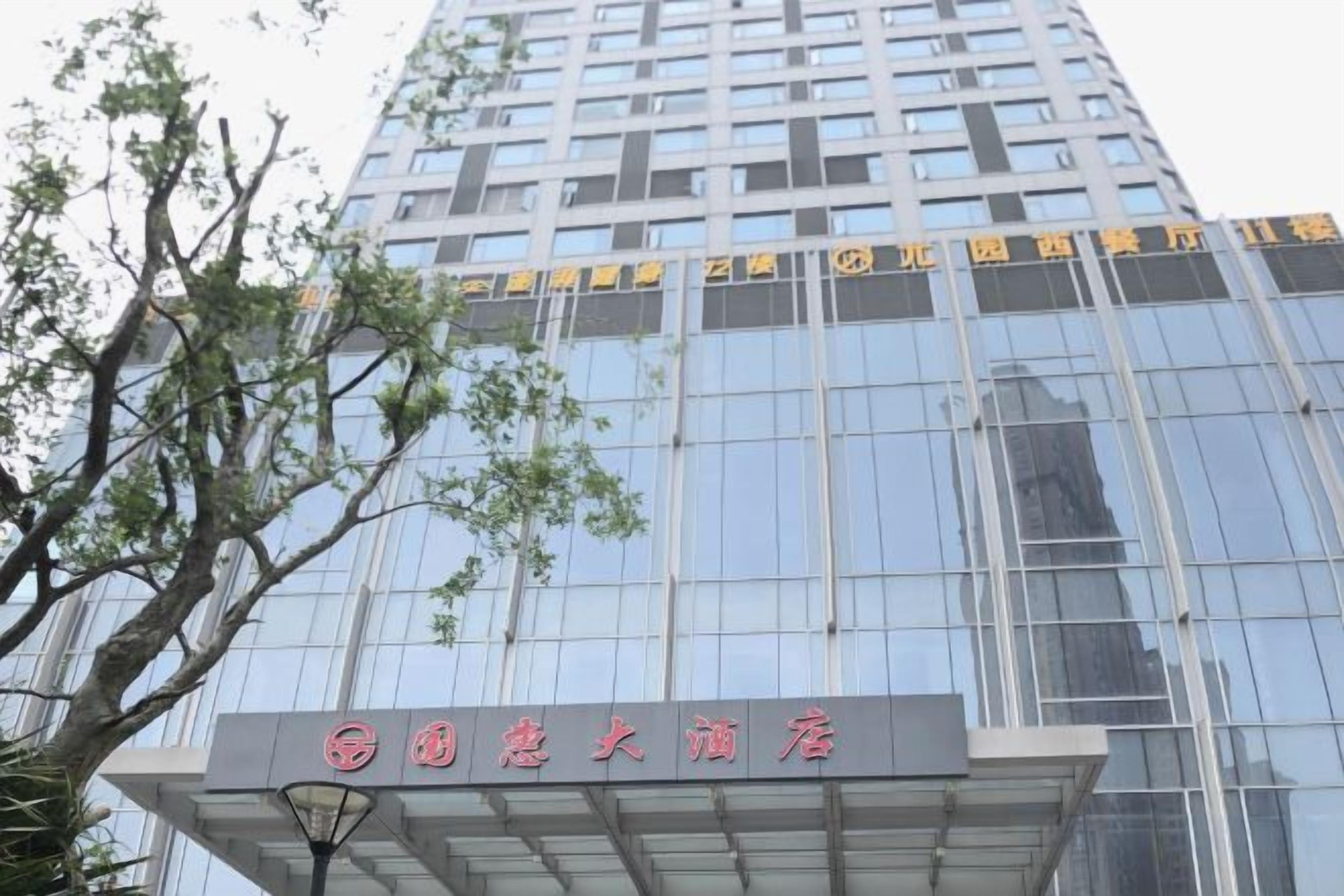 A modern building with a glass facade and a sign indicating it is a hotel.