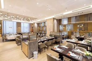 A modern hotel dining area with multiple tables and chairs, a central bar area, and a view of the city through large windows. - Guohui Hotel (Minhou Ganzhe) (Minhou)