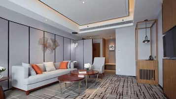 A modern hotel room with a sofa, armchair, coffee table, and a patterned carpet.