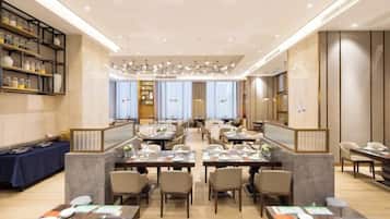 Un comedor espacioso con varias mesas y sillas, una zona de bar central y una pared decorativa con estantes.