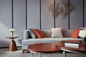 A modern living room with a grey sofa, round coffee table, and decorative wall art. - Guohui Hotel (Minhou Ganzhe) (Minhou)
