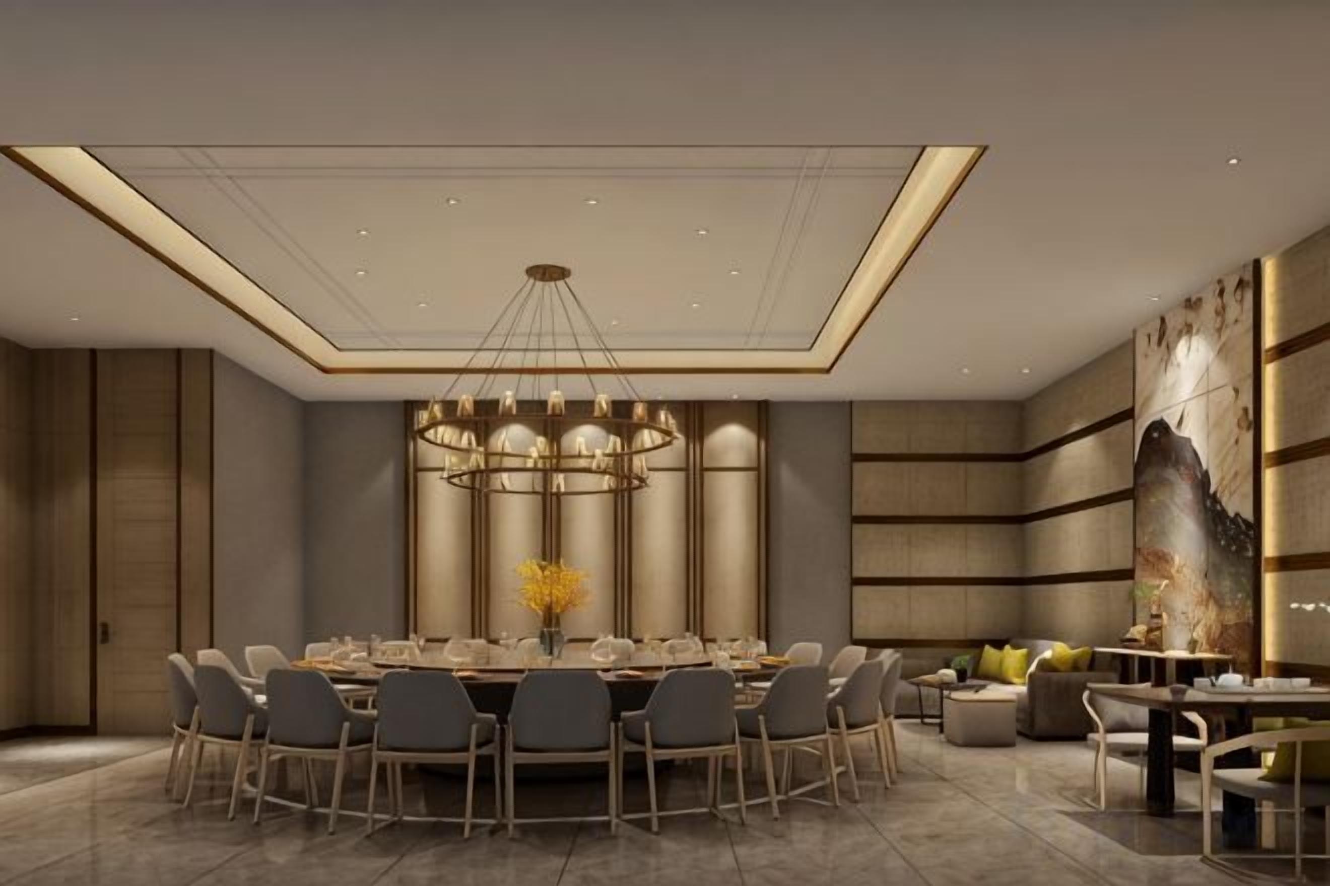 A modern dining area with a round table, chairs, and a chandelier.