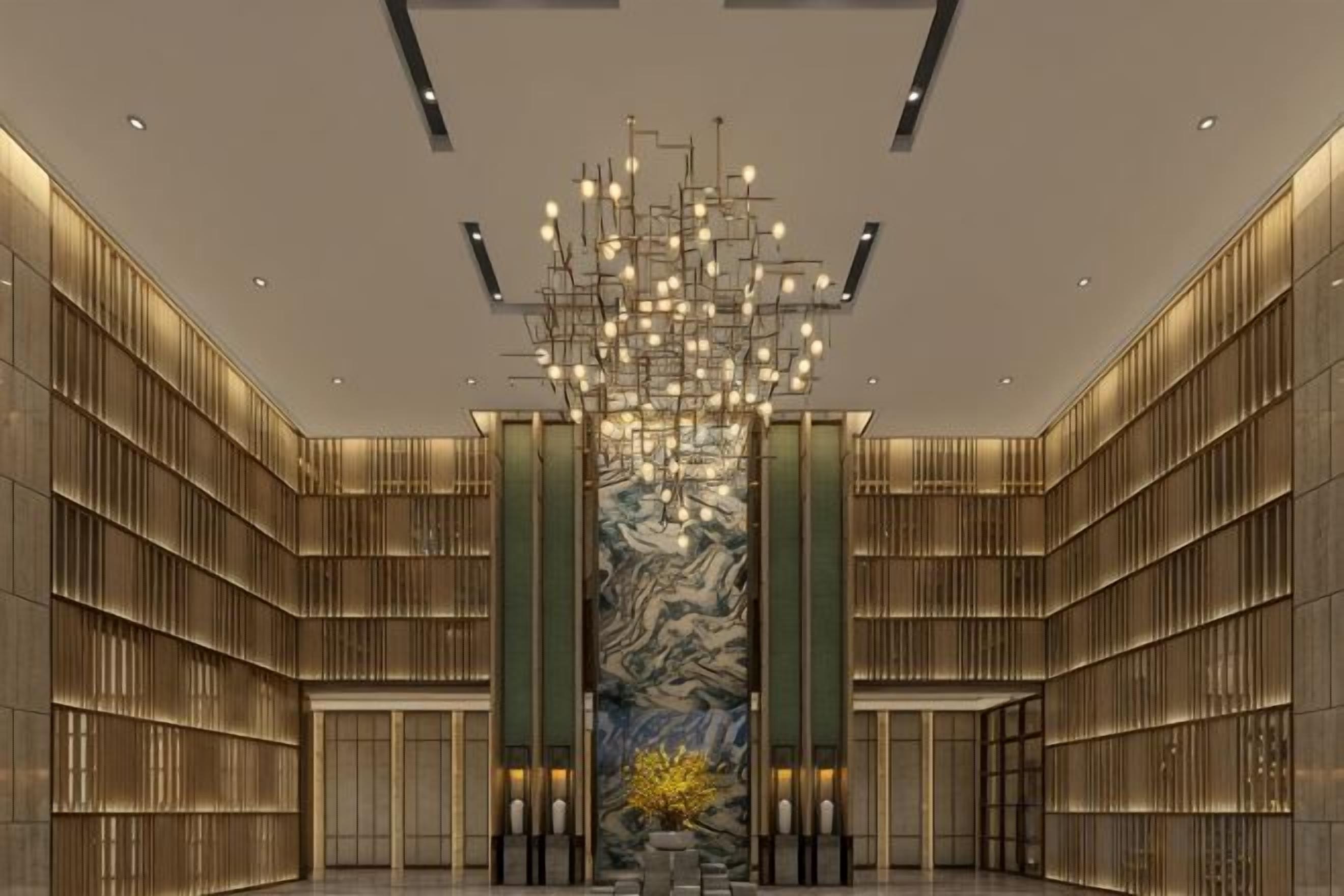 A spacious lobby with a modern chandelier, marble wall, and symmetrical design.