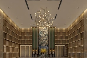 A spacious lobby with a modern chandelier, marble wall, and symmetrical design. - Guohui Hotel (Minhou Ganzhe) (Minhou)