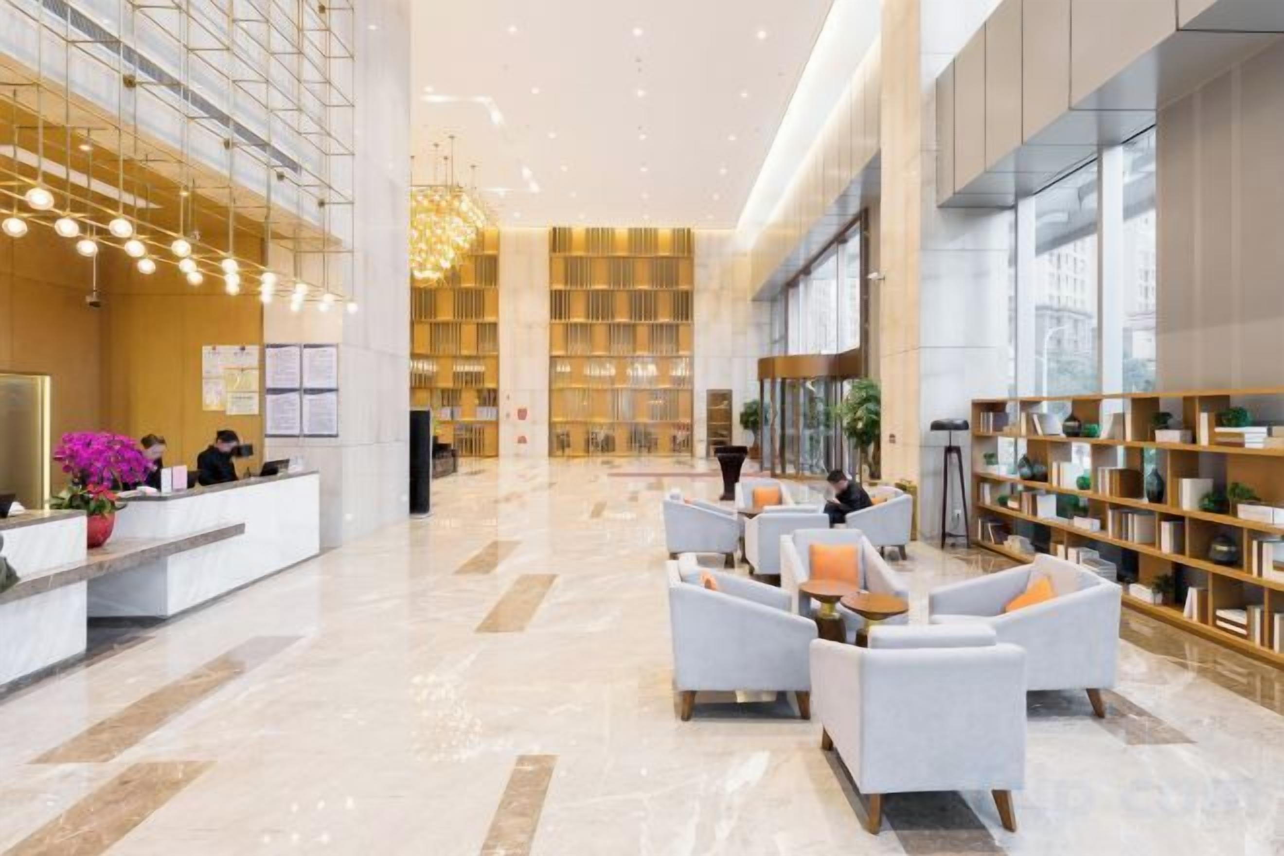 A spacious lobby with a reception desk, seating area, and bookshelves.