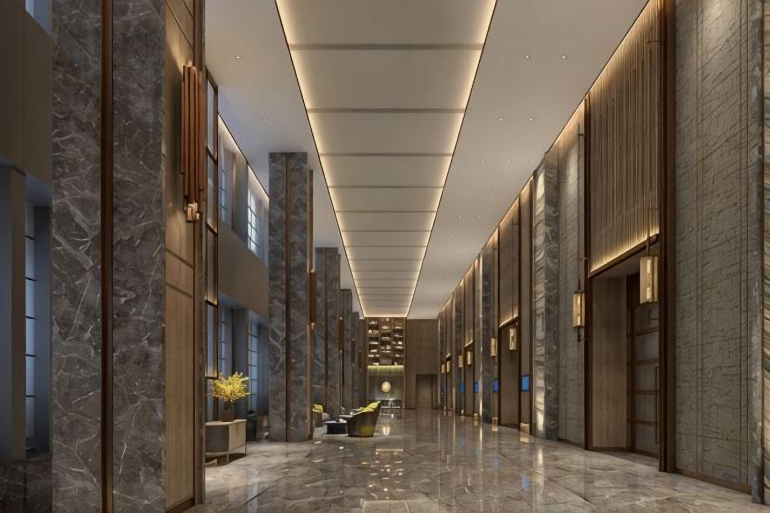 Um corredor com paredes de mármore, iluminação embutida e piso polido.
