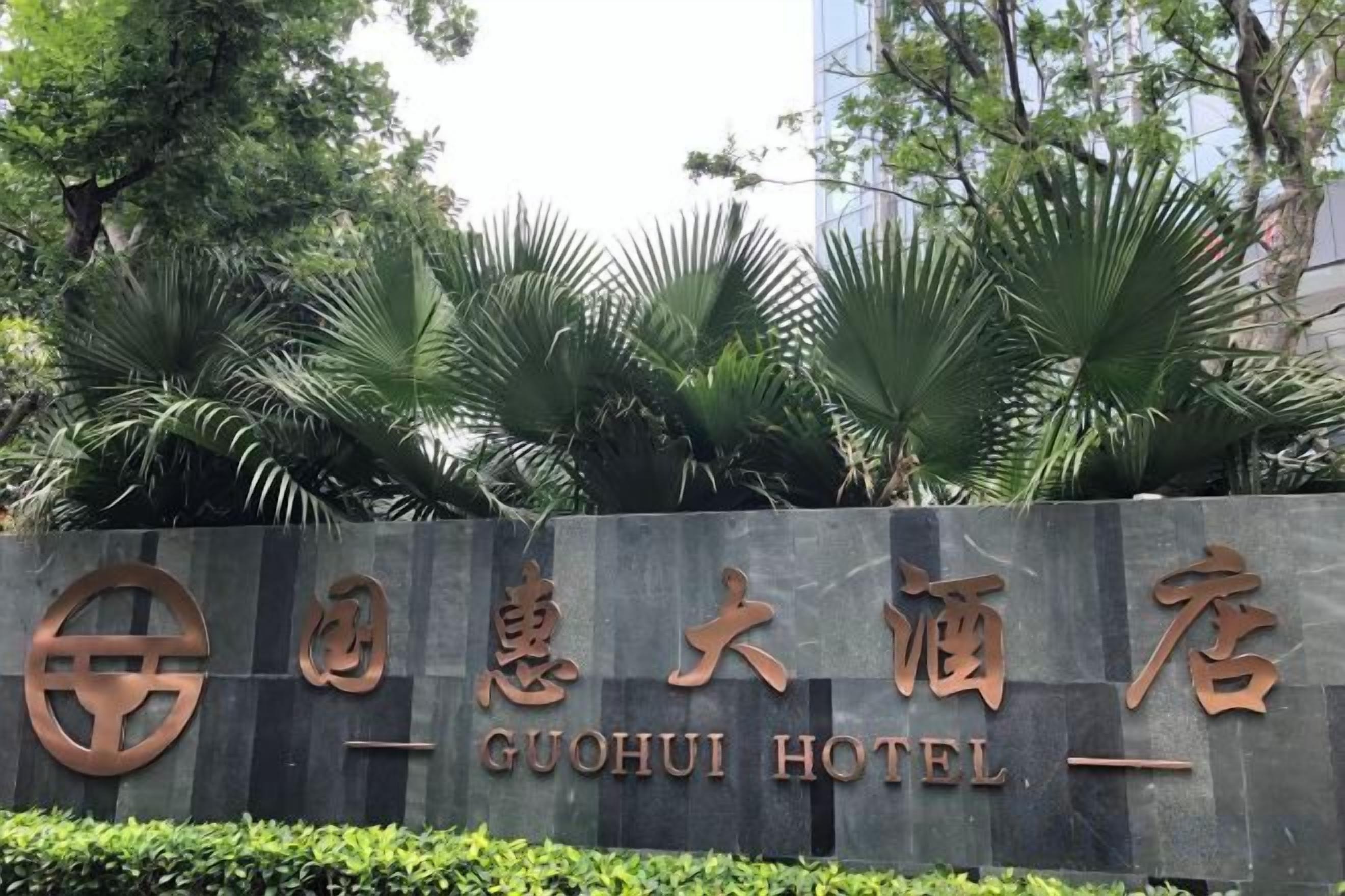 A sign for Guohui Hotel with a modern design, featuring a logo and the hotel's name in large characters.
